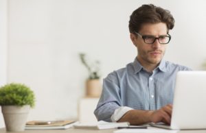 Concentrated Millennial Guy Working On Laptop At Work